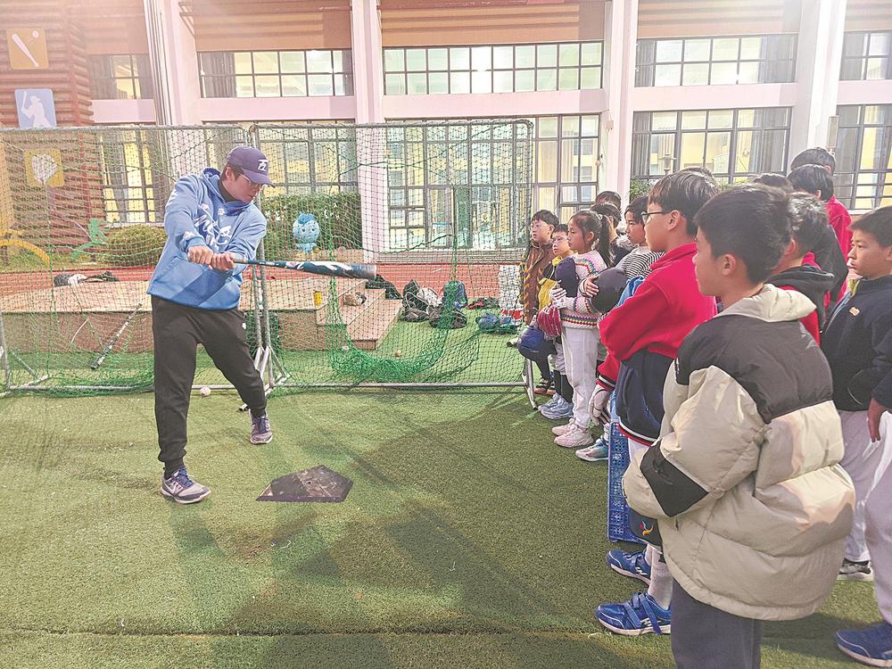 台湾棒球教练董士豪（左）在魁岐小学指导学生打棒球。吴洪 摄