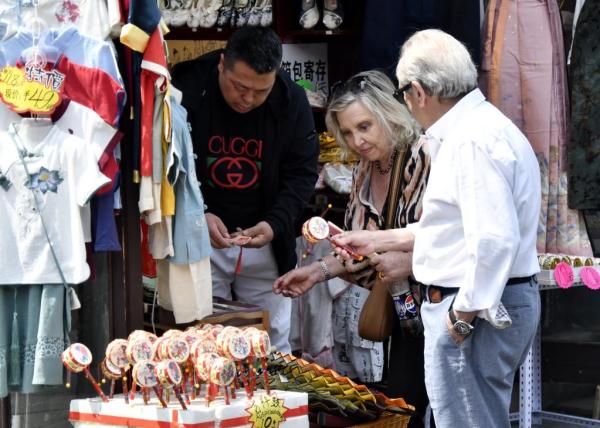 5月1日，来自西班牙的游客在北京烟袋斜街购买纪念品。新华社记者 李欣 摄 